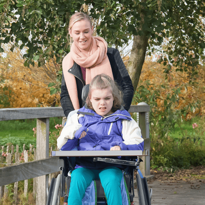 a woman walking and with a young girl in a wheelchair