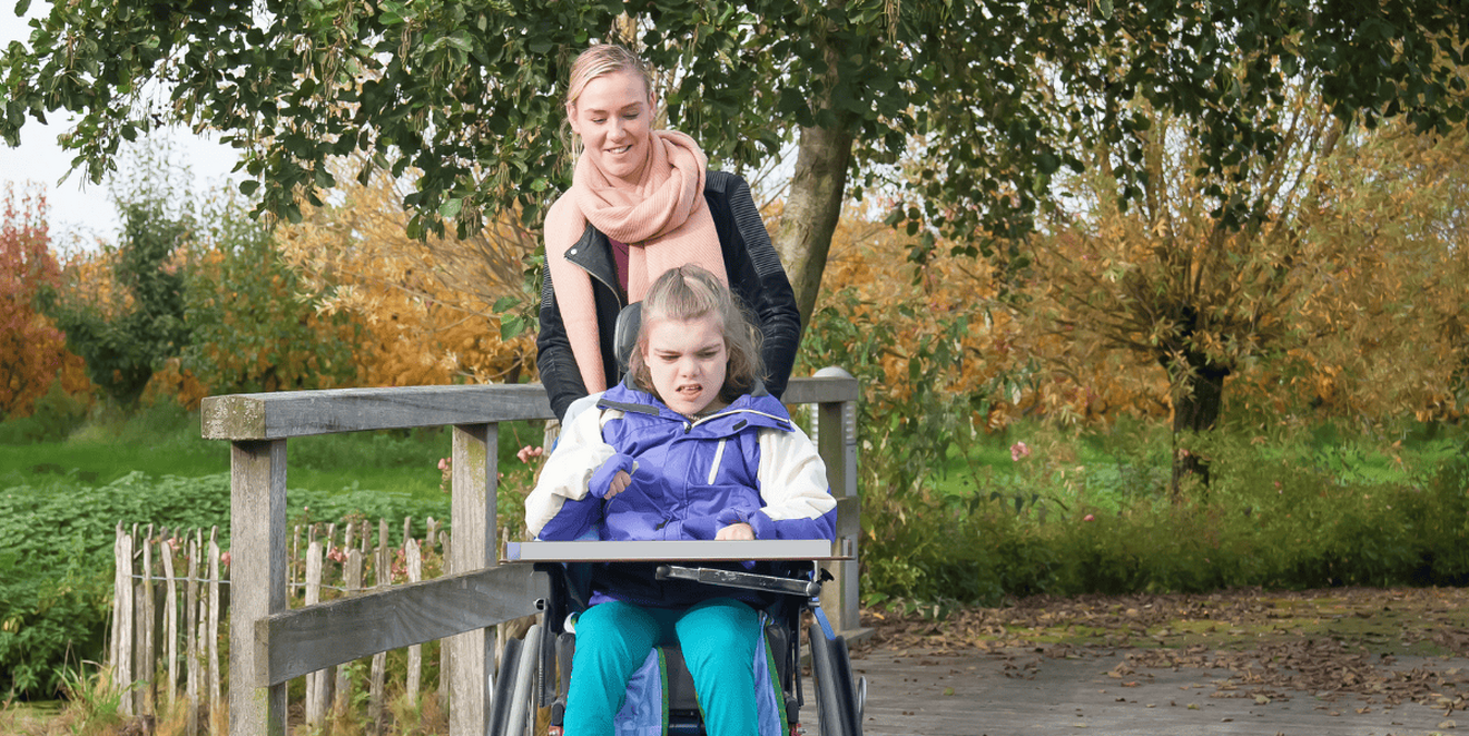 a woman walking and with a young girl in a wheelchair