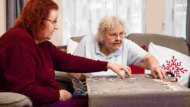 two women completing a puzzle